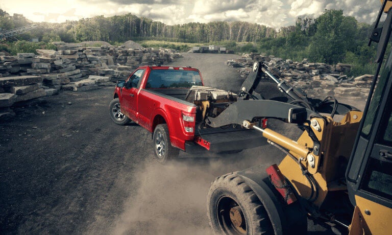 Bulldozer loading rocks into Ford F-150 bed